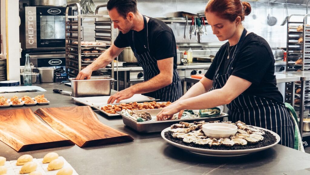 Two chefs preparing a catering meal in the kitchen.