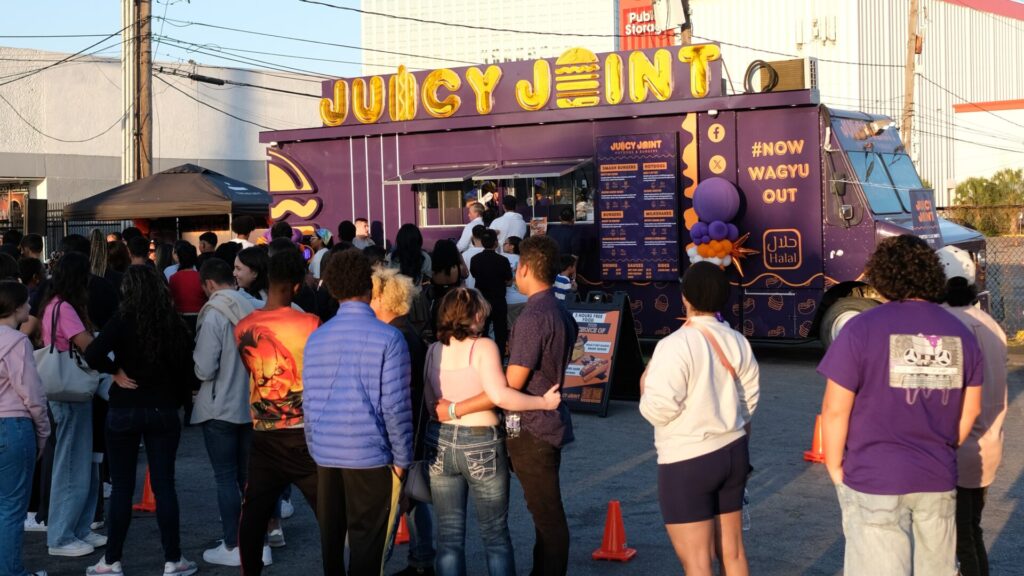 Crowd of people in front of the Juicy Joint food truck for their grand opening event.