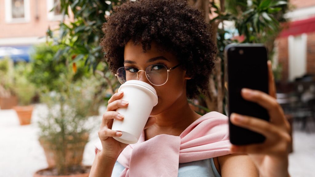 Woman with phone in hand drinking coffee